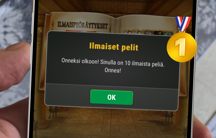 Kuvassa Pelikaani-kasino auki puhelimessa Rahapelisanomien testissä. Vieressä oleva kultamitali symboloi sitä että Pelikaani oli rahapelisanomien paras kasino testivoittaja.