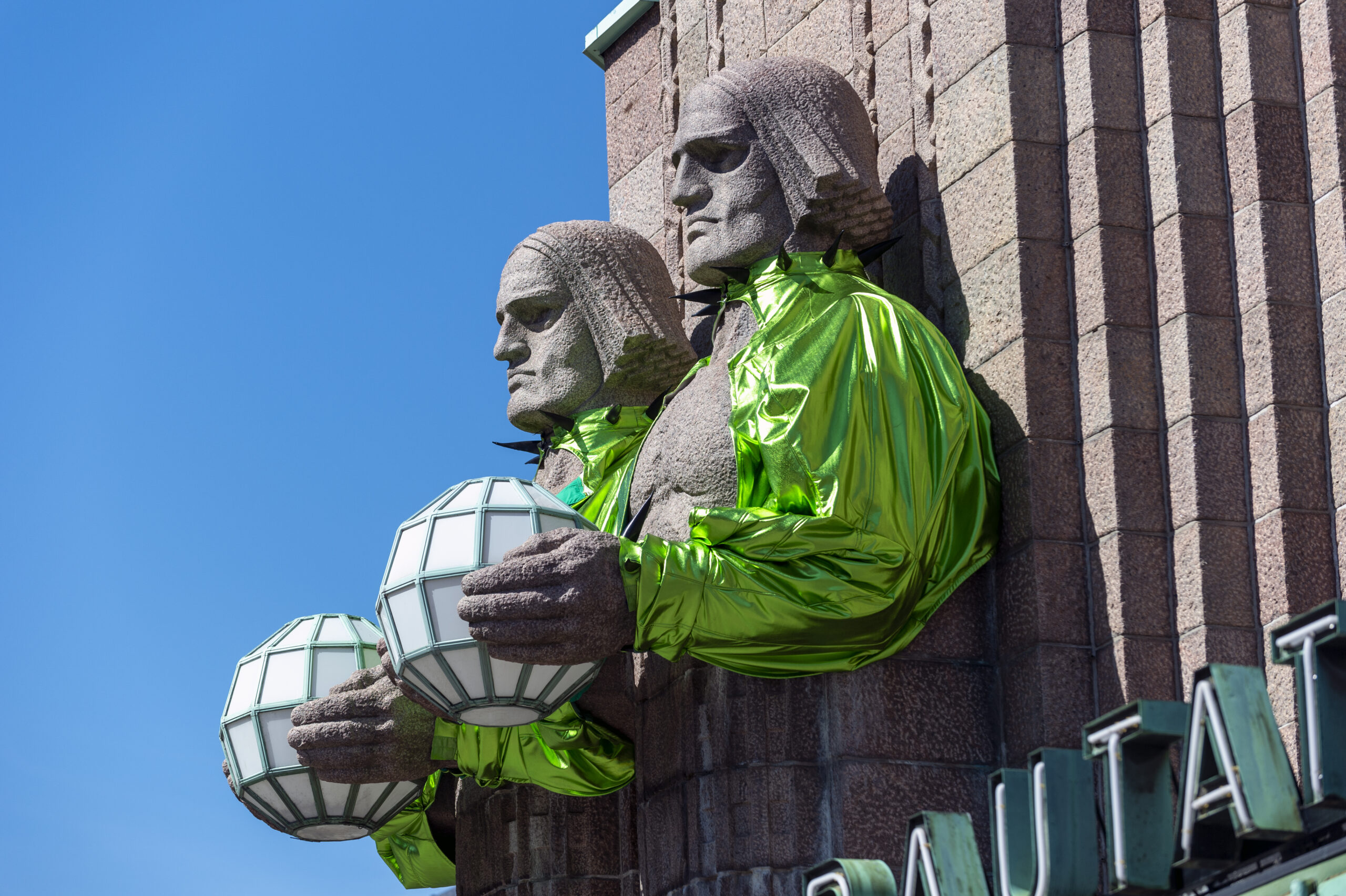 Käärijä asuihin pukeutuneet Lyhdynkantaja patsaat Helsingin rautatieasemalla.