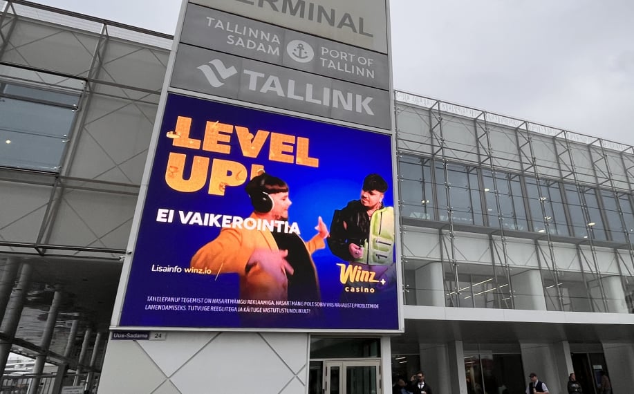Tallinnan sataman terminaalin ulkoseinällä suuri valomainos, jossa mainostetaan Winz Casinoa tekstillä ”Level up! Ei vaikeointia”, kuvassa kaksi henkilöä Käärijän tyyliin pukeutuneina.