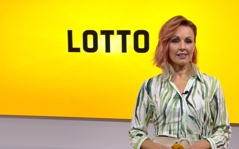 Lotto-arvonnan juontaja studiossa keltaisen taustan edessä, jossa lukee LOTTO.