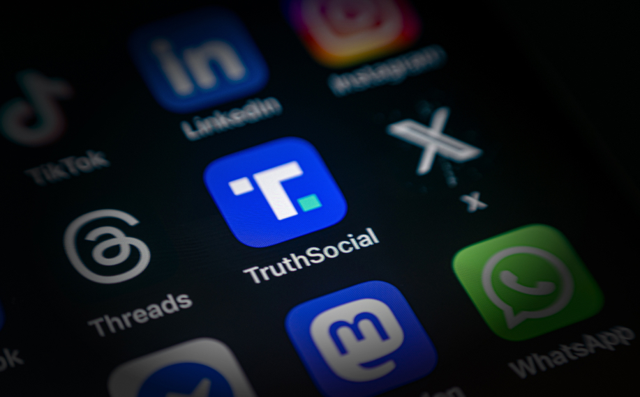 Truth Social appikuvake iPhonen näytöllä. Vieressä Threads ja X.