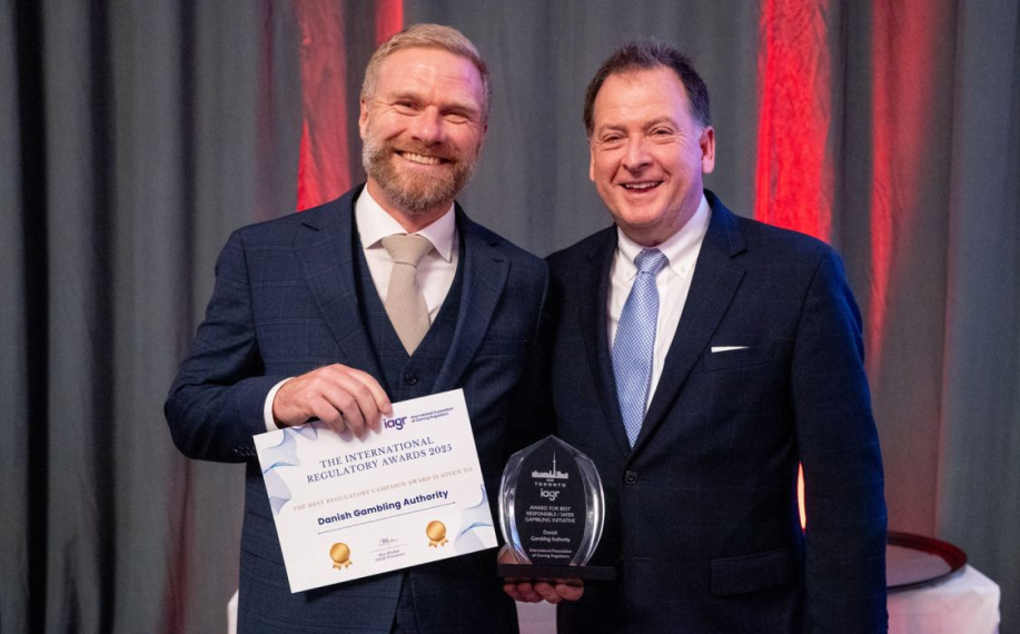 Tanskan peliviranomainen hymyilee ottaessaan vastaan Regulaattorien vuosikokouksen paras kampanja -palkintoa.
