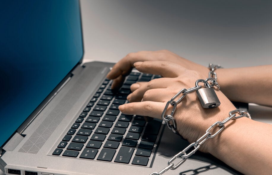 Kädet kahlittu ketjuihin kirjoittamalla kannettavan näppäimistö. Kuvaa haitallista rahapelaamista.