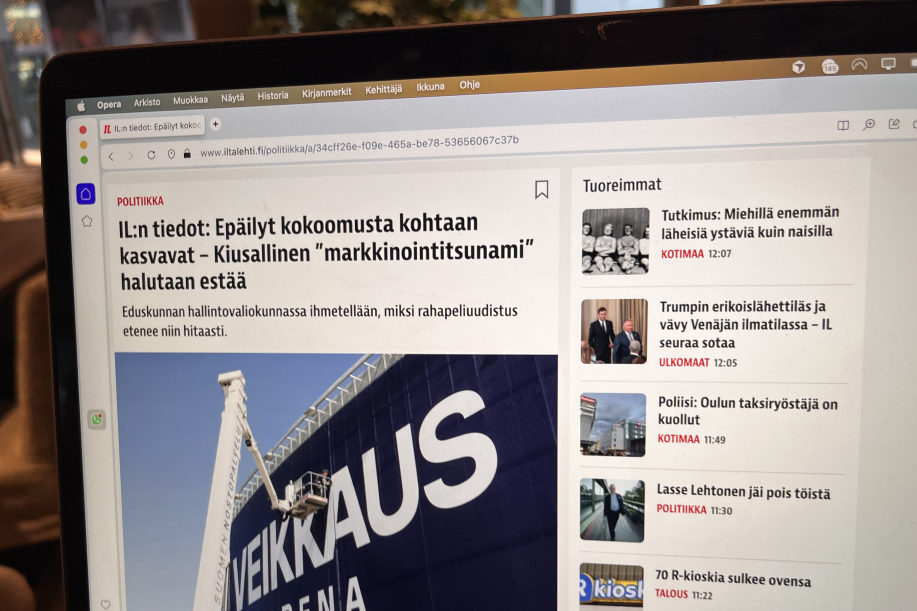 Kuvassa auki tietokonella Iltalehden verkkosivusto missä otsikko "IL:n tiedot: Epäilyt kokoomusta kohtaan kasvavat – Kiusallinen "markkinointitsunami" halutaan estää". Artikkelikuvassa asennetaan Veikkaus Arena plakaattia.