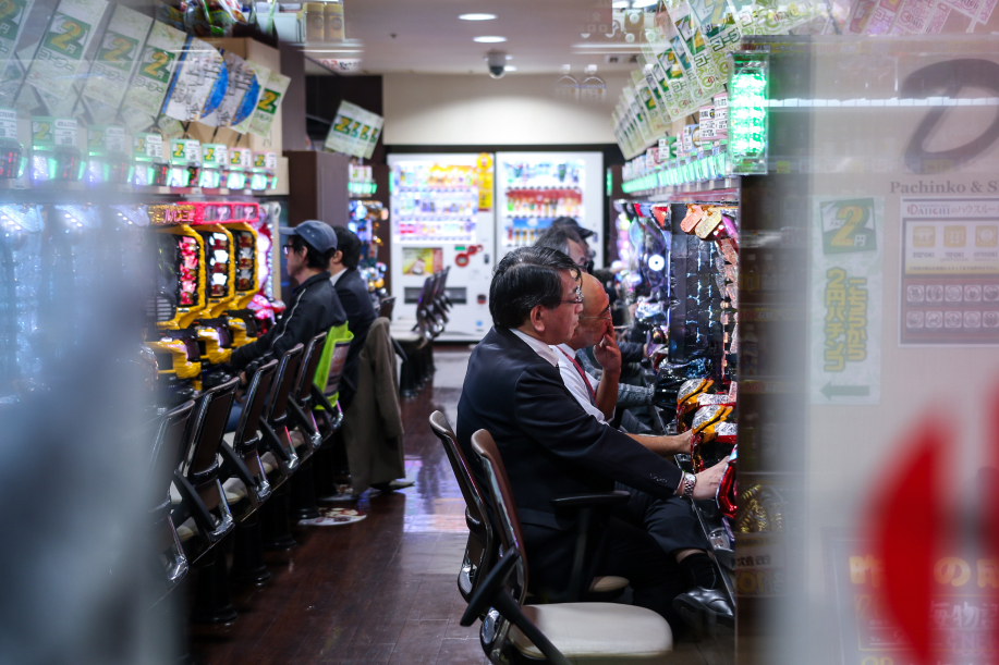 Miehet pelaavat riveihin pistetyillä Pachinko-automaateilla Japanissa