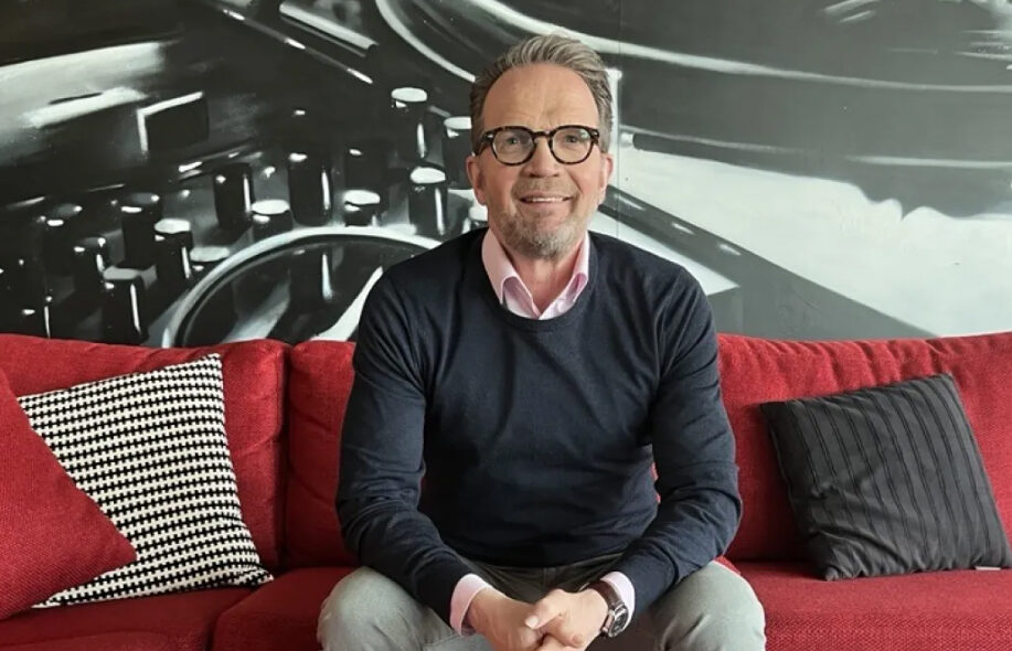 Nummikoski Veikkauksen toimistolla soffalla hymyillen.