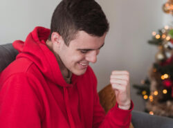 Mies juhlii kasinopeliä, taustalla joulukuusi.