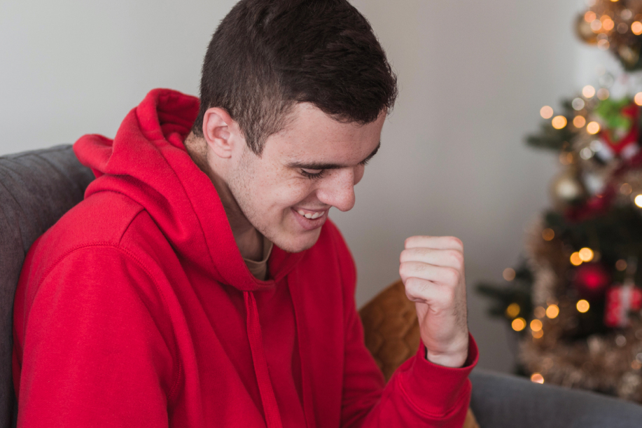 Mies juhlii kasinopeliä, taustalla joulukuusi.