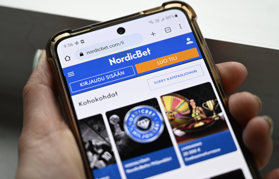 NordicBetin mobiilisivusto älypuhelimella, etusivulla kirjautumis- ja tilinluontipainikkeet.